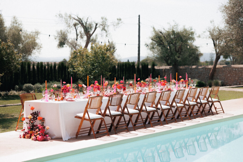 Lange Hochzeitstafel am Pool der Finca Morneta mit Blush-, Peach- und Pink-Dekoration